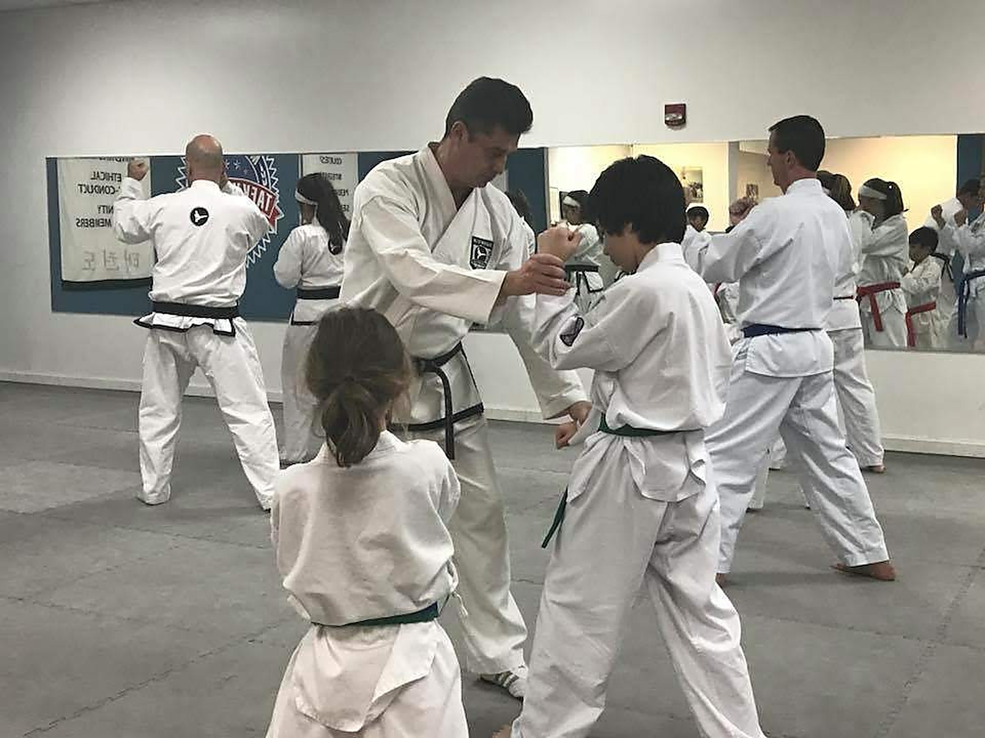 Michael O&rsquo;Malley correcting a student&rsquo;s guard mid-class on the floor of his Peabody school.