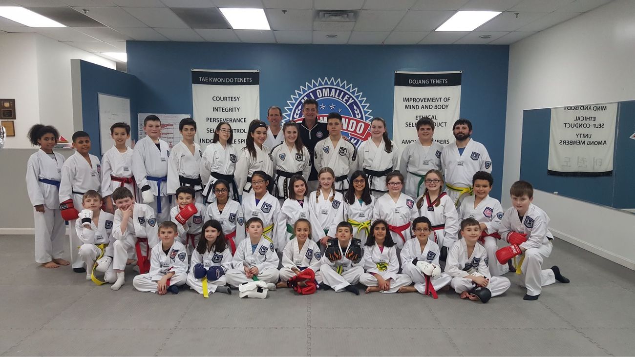 Students of every rank assembled beneath the M.J. O&rsquo;Malley Tae Kwon Do Center crest in Peabody, with Michael O&rsquo;Malley at the centre.